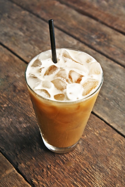 Cup of ice coffee with straw on wooden background