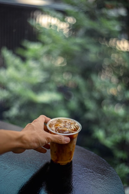 Photo a cup of iced coffee is being held up by a hand.