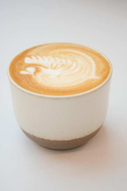 A cup of late coffee with flower shape design on top at cafe