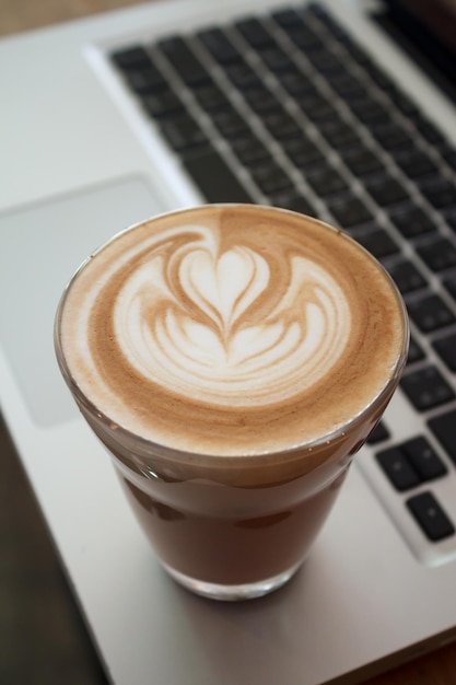 A Cup of latte coffee on laptop keyboard