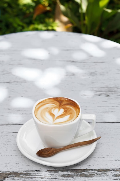 A Cup of latte coffee on white wood table