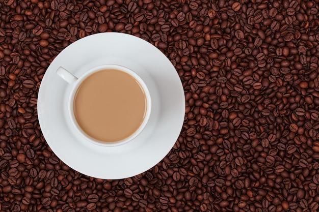 A cup of milk coffee on coffee beans background