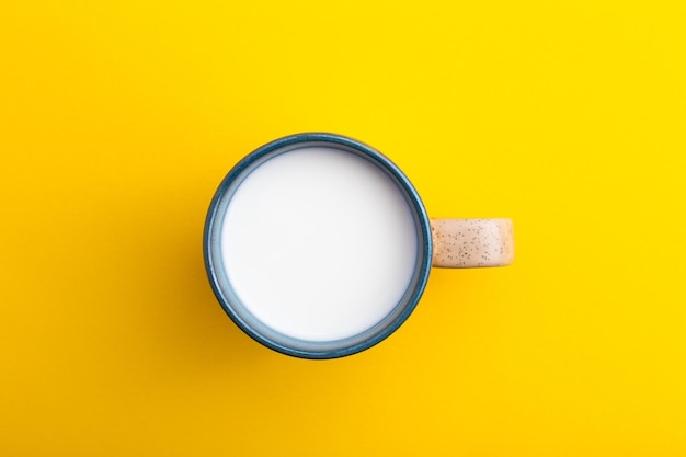 A cup of milk top view on yellow background