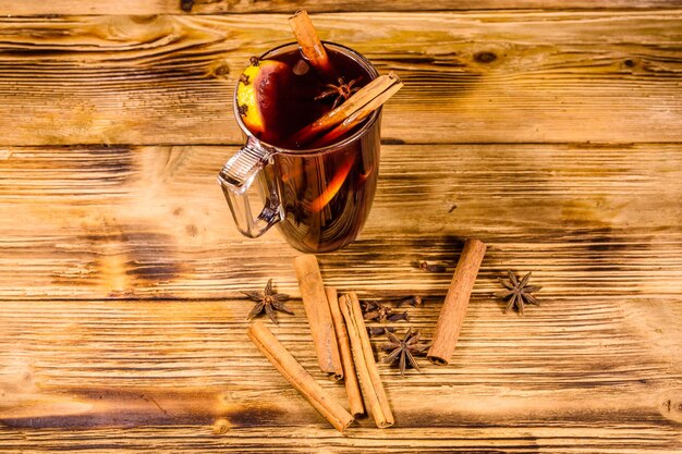 Cup of mulled wine with cinnamon on wooden table