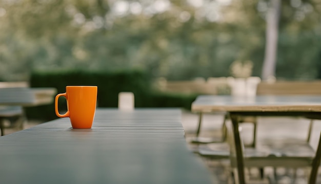 a cup of orange liquid sits on a table with other tables in the background