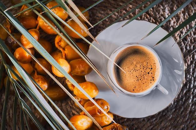 Cup of strong espresso coffee and fresh dates top view Idea for breakfast Date harvest on the farm idea for background or product advertising