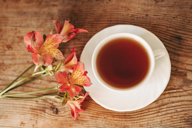 Cup of tea and Alstroemeria on the wooden background. flowers on a brown background. copy text. beautiful bouquet.