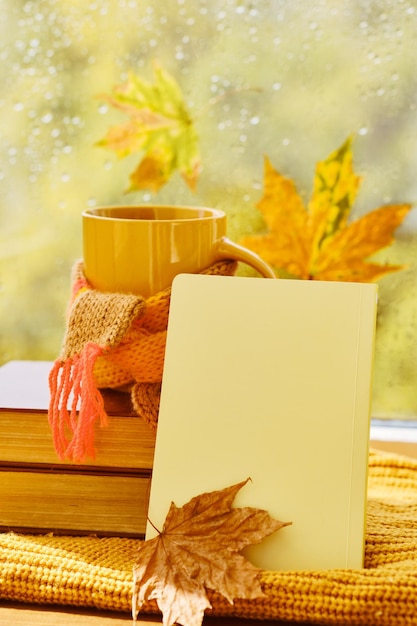 Cup of tea autumn leaves books notebook and red knitted plaid on wooden table