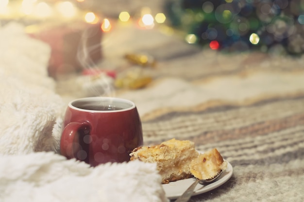 Cup of tea on a background of a Christmas tree with luminous lights and gifts