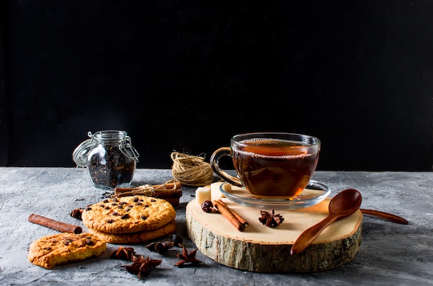 Cup of  tea, biscuits, cinnamon, anise on dark   background