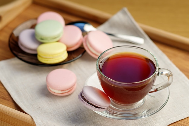 Cup of tea and colorful macaroons on a wooden tray 