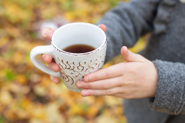 Cup of tea in hand outdoor. Walk in the autumn forest - Image