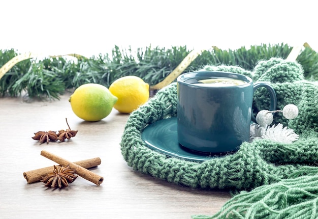 A cup of tea on a knit winter scarf closeup on a wooden table