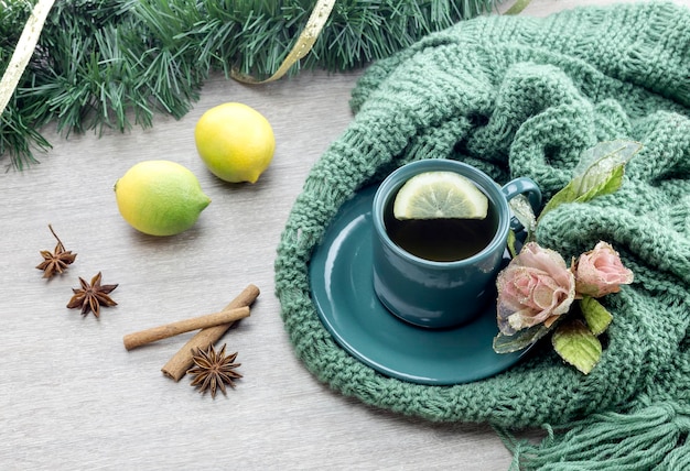 A cup of tea on a knit winter scarf closeup on a wooden table