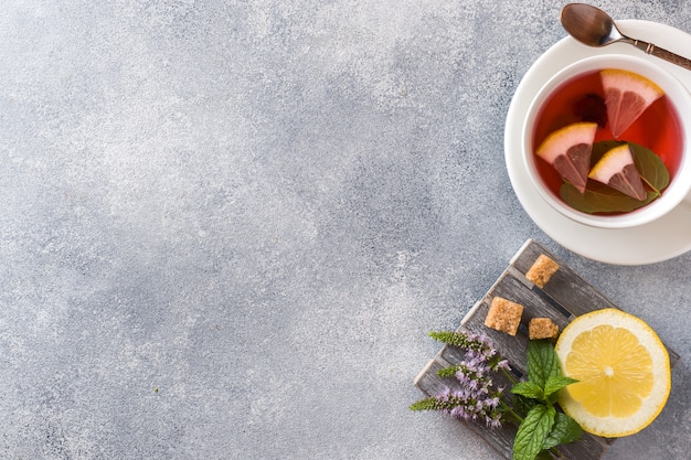 Cup of tea, mint and lemon on grey table with copy space