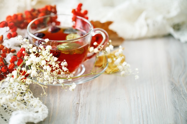 A Cup of tea and Rowan berries on a wooden table. Autumn still-life.