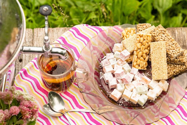 A Cup of tea and a samovar on a wooden table with sweets.