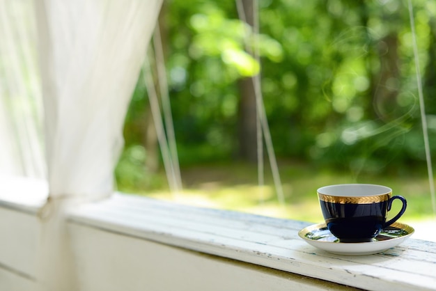 Cup of tea on summer green garden Hot drink in blue cup in garden terrace Cup with hot black coffee