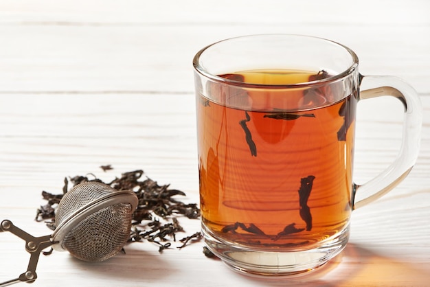 Cup of tea and teastrainer on wooden background