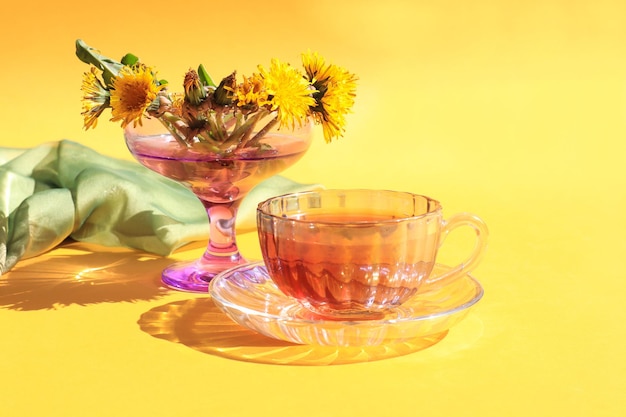 A cup of tea with a bouquet of dandelions on a yellow background a place for text