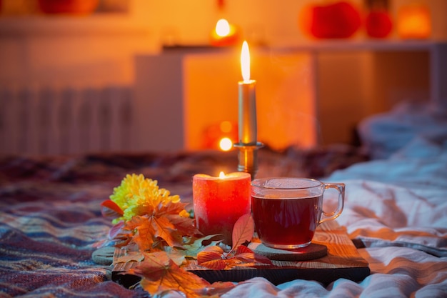 Cup of tea with burning candles in bedroom