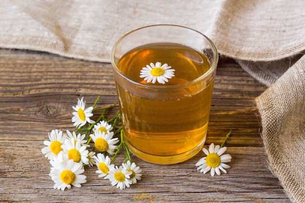 Cup of tea with chamomile flowers on rustic wooden background