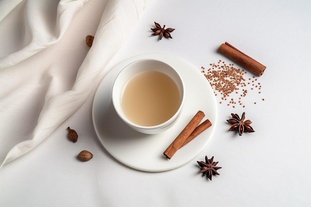 A cup of tea with cinnamon and anise star on the side