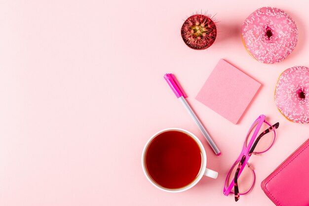 Cup of tea with donuts on a pink pastel background