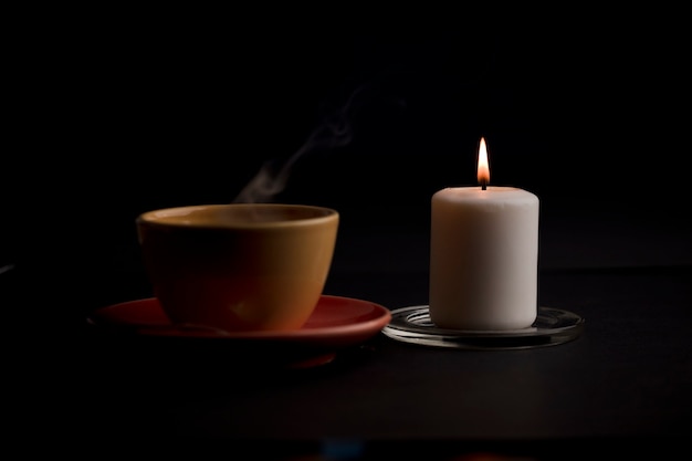 cup of tea with hot smoke and lit candle on the desk at home power outage