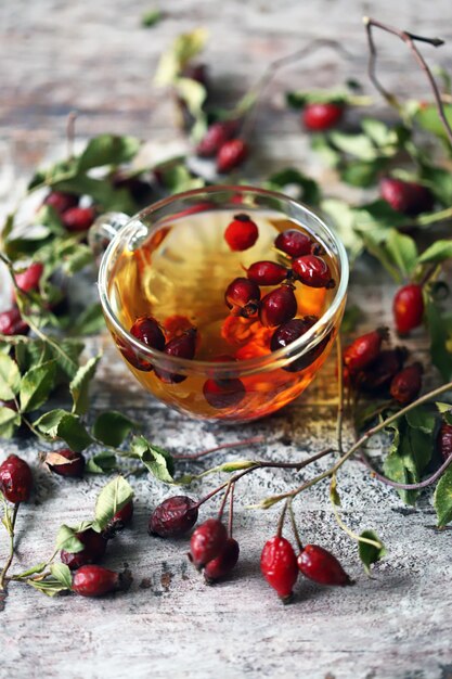 A cup of tea with rose hips. Branches and berries of wild rose. Autumn healing drink. Selective focus. 