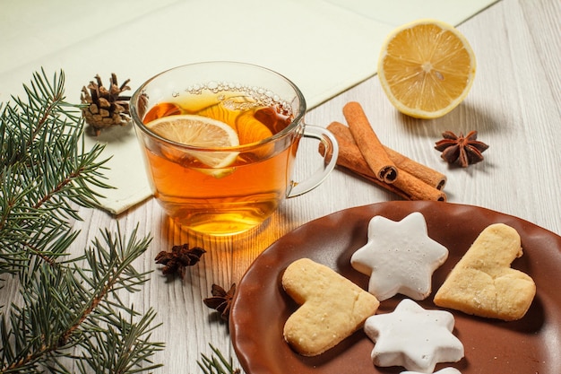 Cup of tea with slice of lemon gingerbread cookies and branch of fir tree