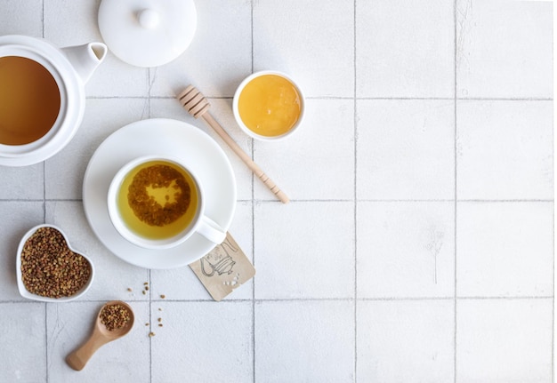 A cup of tea with a spoon and a cup of tea on a white tile background.