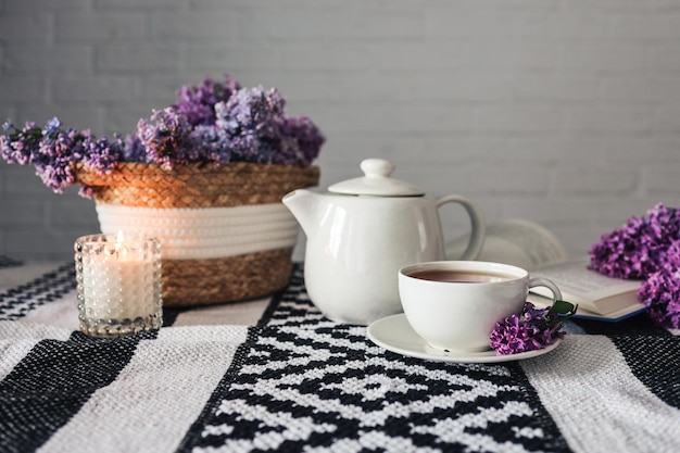 A cup of tea with a teapot on a table with a lilac wicker basket atmospheric tea party photo