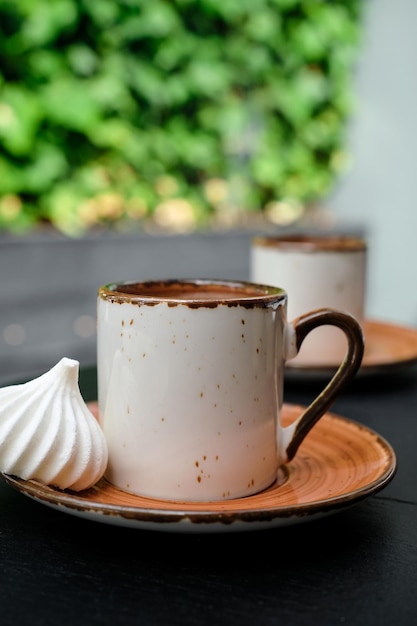 Cup of Turkish black frothy coffee on a black stone table with branches of wild ivy in the background bizet next to the cup Vertical frame selective focus