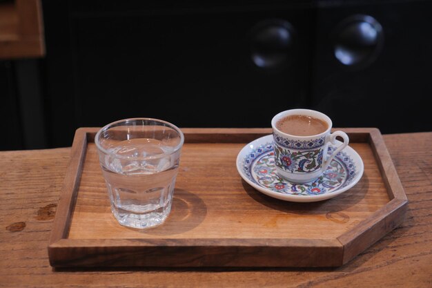 A cup of turkish coffee and glass of water on table