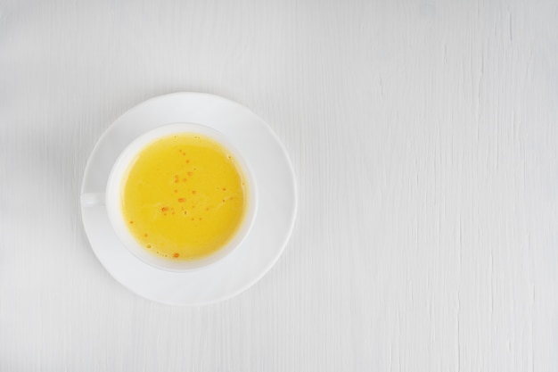 cup of turmeric milk served on plate on white wooden table