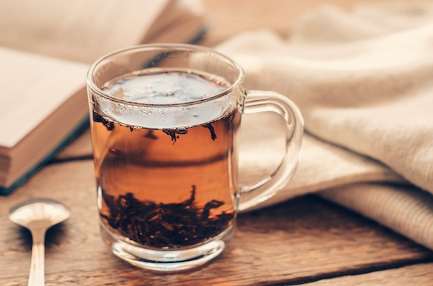 A cup with black brewed tea on a wooden table with book