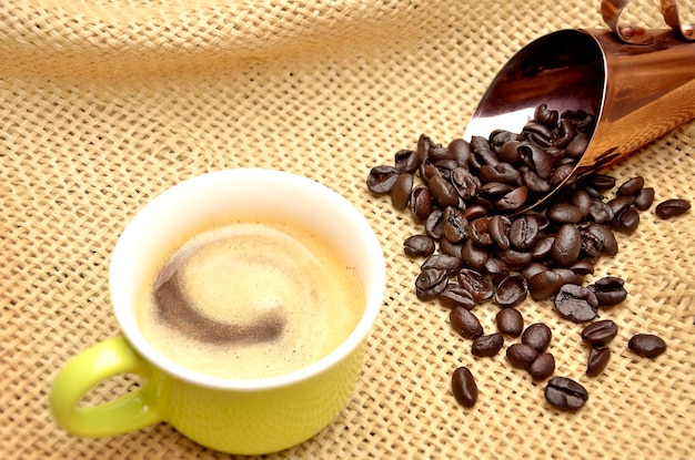 cup with coffee and roasted coffee beans in the shell