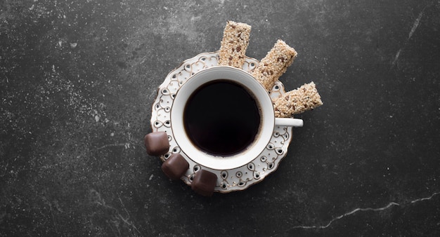 Cup with coffee and sweets on a saucer a delicious snack on a dark background