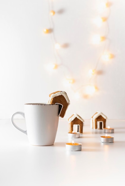 Cup with gingerbread houses and candles on white background Vertical frame