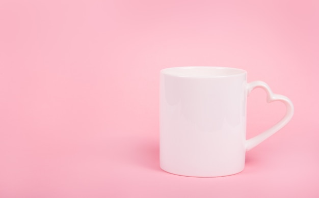 Cup with heart on pink background