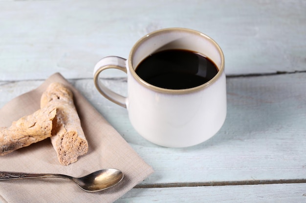 Cup with hot coffee on color wooden background