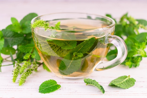 Cup with mint tea on a white wooden background.Close-up.