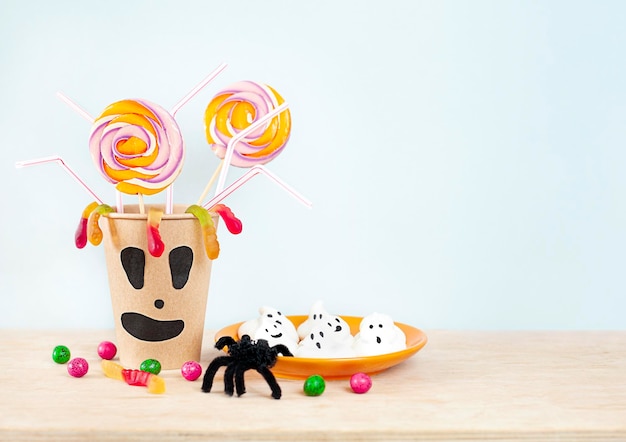 cup with sweets and cakes close-up on a blue background. halloween concept