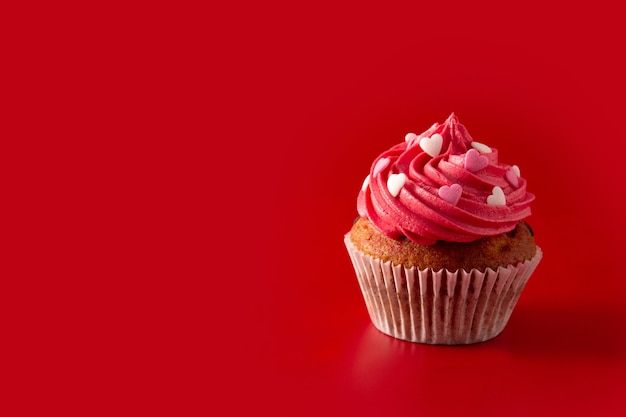 Cupcake decorated with sugar hearts for Valentine's Day on red background