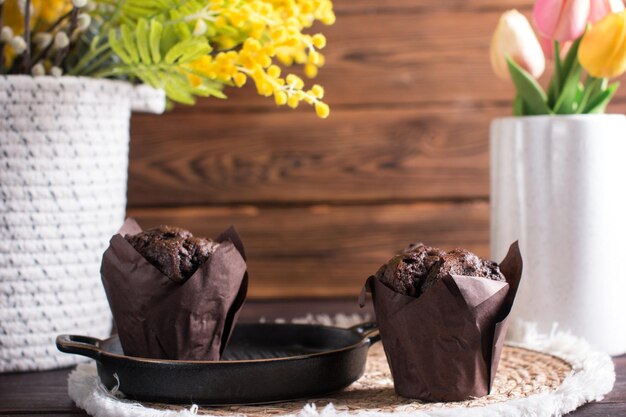 Cupcake muffin with chocolate on a white background with a bouquet of mimosa Congratulations on International Womens Day postcard