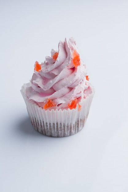 Cupcake with white pink cream and orange fruit juices on white background