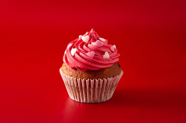 Cupcakes decorated with sugar hearts for Valentine's Day on red background