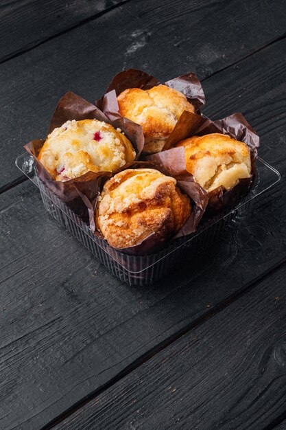 Cupcakes, in plastic container box, on black wooden table background with copy space for text