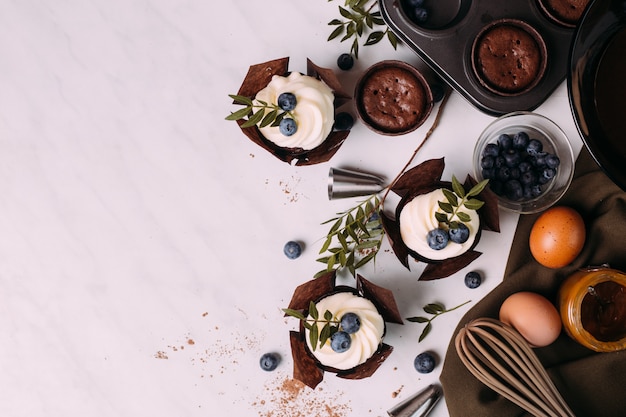 Photo cupcakes with cream and blueberries on kitchen table